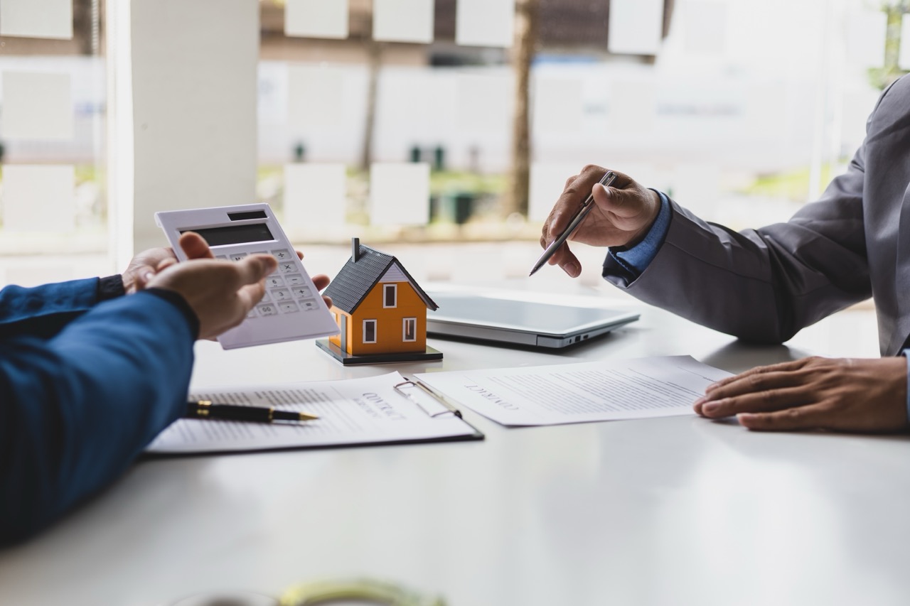 Corretores de imóveis discutindo taxas e orçamentos com clientes após acordo de compra de casa e terreno.