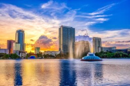 Pôr do sol e nuvens sobre o horizonte de Orlando com vista para a fonte no Lake Eola Park, Orlando, Flórida.