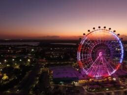 Vista noturna da roda-gigante iluminada do ICON Park em Orlando, com a cidade ao fundo