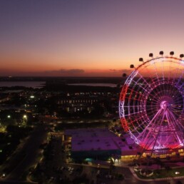 Vista noturna da roda-gigante iluminada do ICON Park em Orlando, com a cidade ao fundo