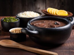 Feijoada, prato típico brasileiro feito com feijão preto, servido em uma panela de barro.