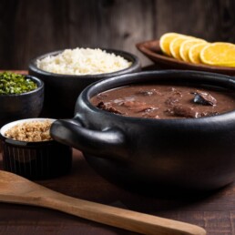 Feijoada, prato típico brasileiro feito com feijão preto, servido em uma panela de barro.