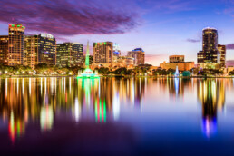 Skyline do centro de Orlando, Flórida, vista do Eola Park, com prédios altos e o lago ao fundo.