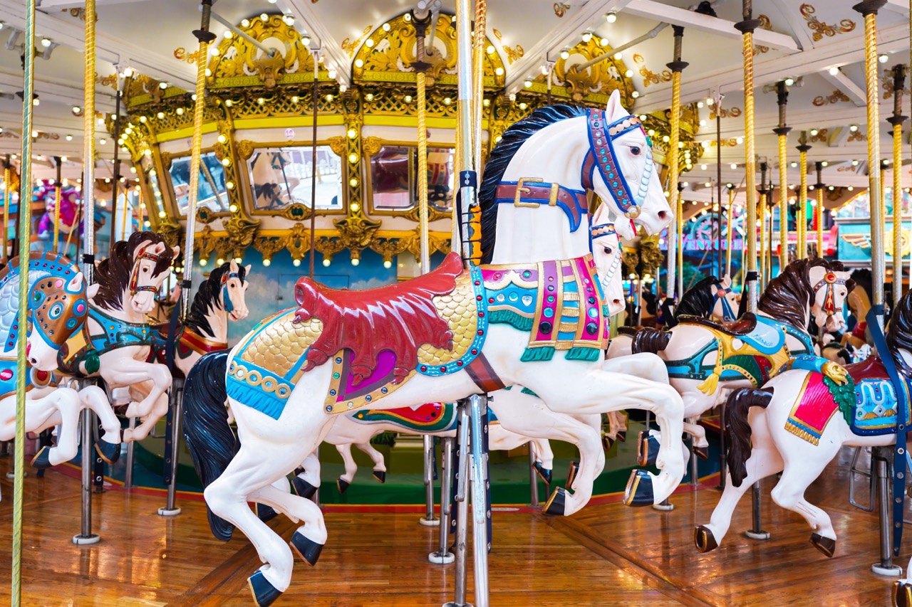 Carrossel com cavalos coloridos e detalhes dourados, capturado em um ambiente iluminado.